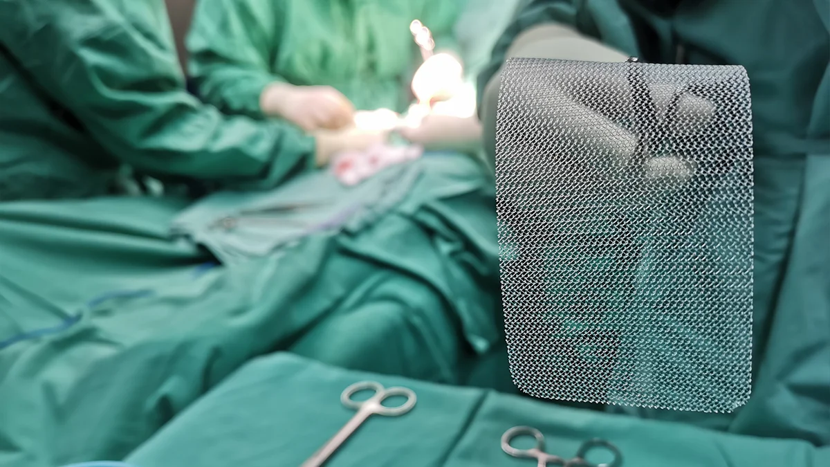 A surgeon holds a synthetic mesh for treating hernias with tweezers during surgery